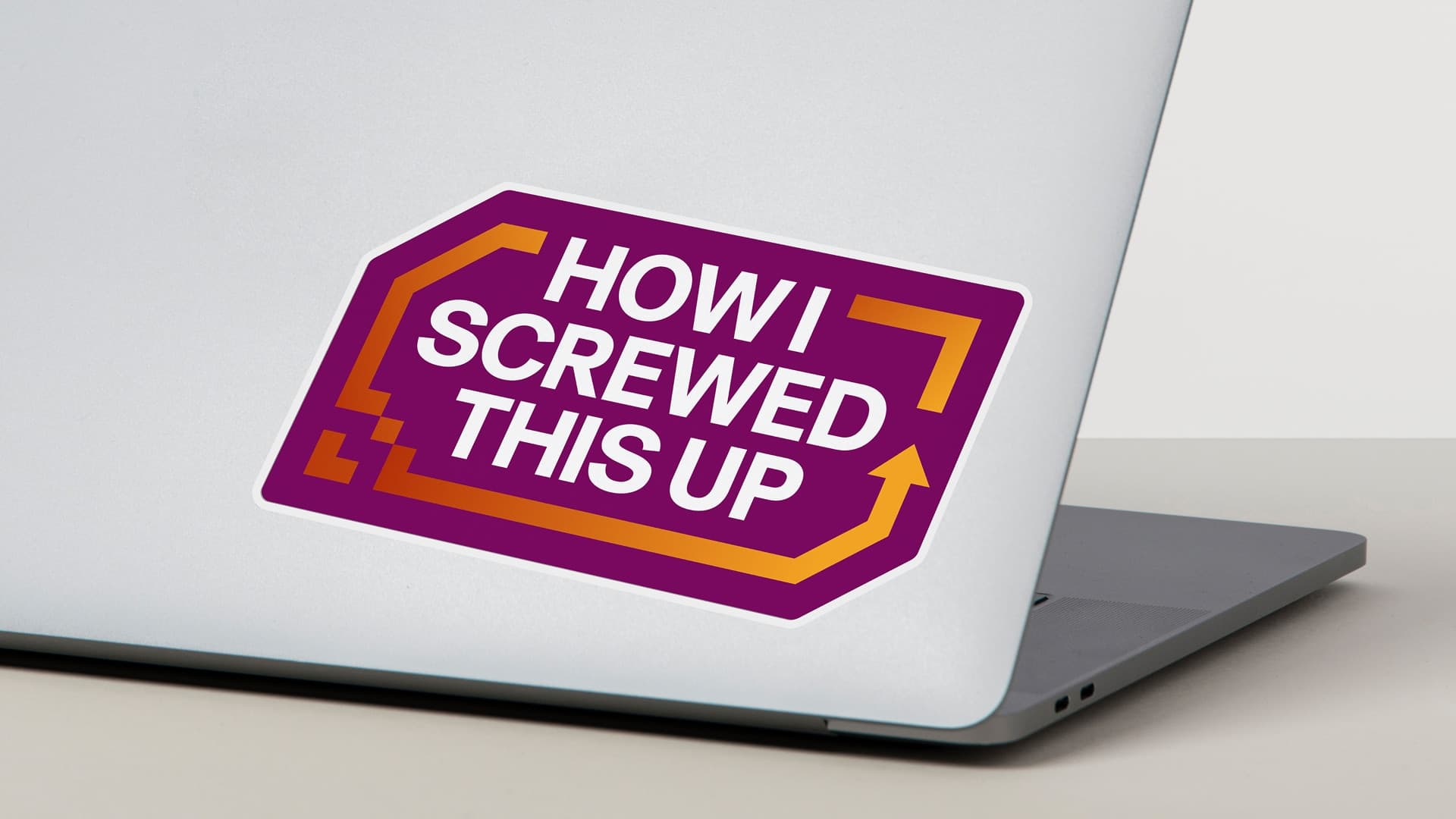 Photograph of a laptop with a sticker on the cover that says How I Screwed This Up