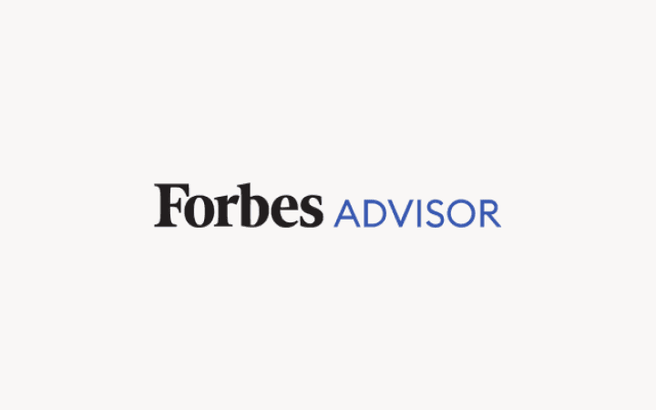 Forbes Advisor logo with black "Forbes" text and blue "ADVISOR" text on a light pink background.